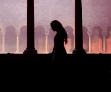 a silhouette of a woman standing in front of a window