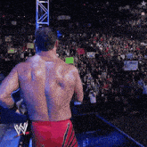 a shirtless wrestler stands in front of a crowd holding a sign that says ' i love you ' on it