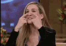 a woman is covering her nose with her hands while talking on a television show .