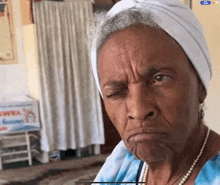 an older woman wearing a white turban and pearls looks at the camera