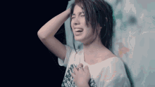 a woman in a white shirt is laughing with her hand on her head