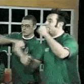 two men in green shirts are standing next to each other and one of them has the number 1 on his shirt