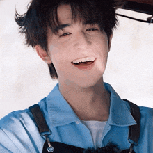 a young man wearing a blue shirt and an apron smiles