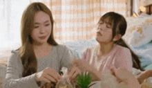 two women are sitting at a table in a room eating food .