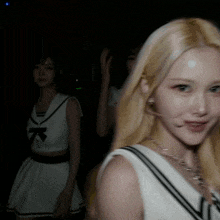 a blonde woman wearing a headset looks at the camera in the dark