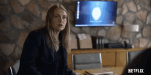 a woman is sitting at a table in front of a tv in a room .