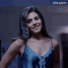 a woman in a blue top is smiling and looking at the camera