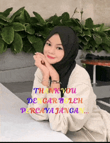a woman wearing a hijab is sitting at a table with the words thank you dengar boleh percaya jangan