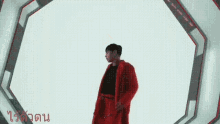 a man in a red coat is standing in a room with a white background .