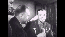 a man in a military uniform is holding a microphone and talking to another man