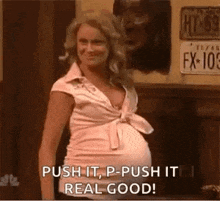 a pregnant woman is standing in front of a sign that says push it , p - push it real good .