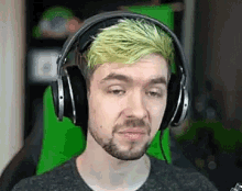 a man with a beard and green hair is wearing headphones .