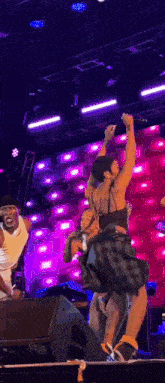 a group of people are dancing on a stage in front of a large microphone .