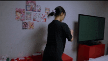 a woman in a black shirt stands in front of a samsung tv