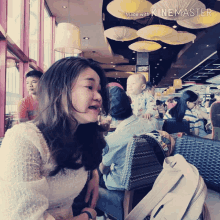 a woman is sitting in a restaurant with a baby in her lap and the words made with kinemaster on the bottom