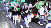 a group of people dancing in front of a wolfe tv bus