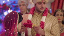 a bride and groom are getting married and the bride is wearing a red and white garland