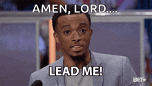 a man in a suit is talking into a microphone and saying `` amen , lord ... lead me ! ''