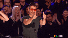a man wearing sunglasses gives a thumbs up in front of a crowd with nbc written on the bottom