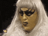 a woman with gold paint on her face is wearing a wrestler 's mask
