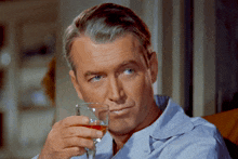 a man in a blue shirt is holding a wine glass