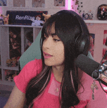 a woman wearing headphones sits in front of a microphone with a sign that says renrize in the background