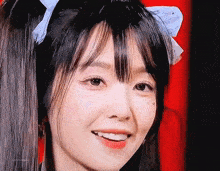 a close up of a woman 's face with a blue bow in her hair
