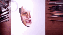 a drawing of a man 's face surrounded by colored pencils and pens
