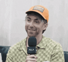 a man wearing an orange hat is holding a microphone that says pulp on it