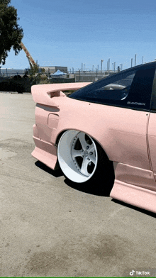 a pink nissan 240sx is parked on a street