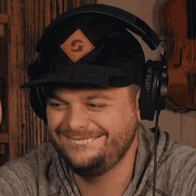a man wearing headphones and a hat with the letter s on it is smiling