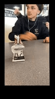 a boy is sitting at a table with a statue of a chicken on it .