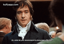 a man in a black coat and white tie is talking to another man .