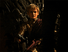 a young man sitting on a throne with a sword