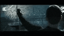 a man is standing in front of a computer screen and pointing at something .