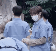 a man wearing a mask and a blue shirt is standing next to another man