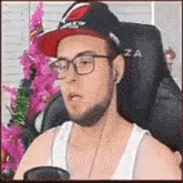 a man wearing glasses and a red hat is sitting in a chair in front of a christmas tree .