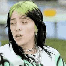 billie eilish is wearing a green and black striped shirt and a choker .