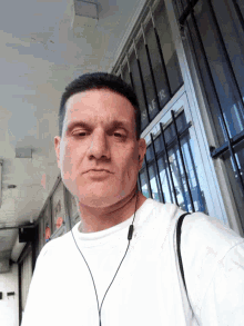 a man wearing ear buds is standing in front of a window with the word s.a.r. written on it