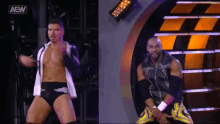two aew wrestlers are standing on a stage in front of a wall