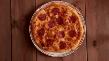 a pepperoni pizza on a white plate on a wooden table