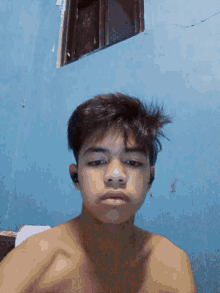 a young man without a shirt is looking at the camera with a blue background