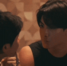 a man in a black tank top is looking at another man in a black tank top