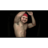 a shirtless man wearing a red bandana is flexing his muscles in a dark room .