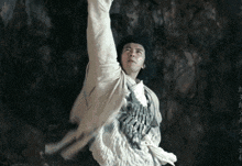 a man in a white shirt and black hat is doing a karate move