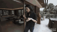 a woman in a black shirt stands in front of a sliding glass door made in animotica