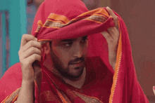 a woman in a pink and blue sari is covering her face with a veil .