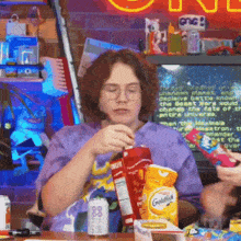 a woman is sitting at a table with a box of goldfish chips in front of her
