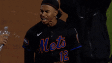 a man in a mets jersey is holding a bottle of water