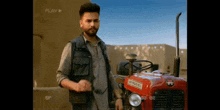 a man is standing next to a red tractor in a field .